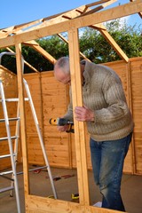 DIY. Senior man at work with a drill on an outside project.