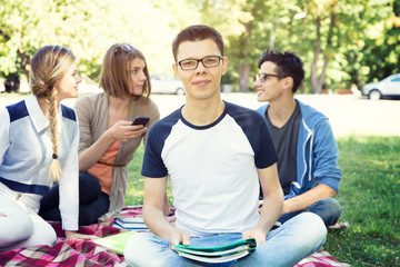 Students life. Group of friends sit together on meadow in the campus university.