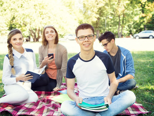 Students life. Group of friends sit together on meadow in the campus university.