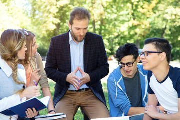 Teacher and group of students outdoors near the university. Training, discussion.