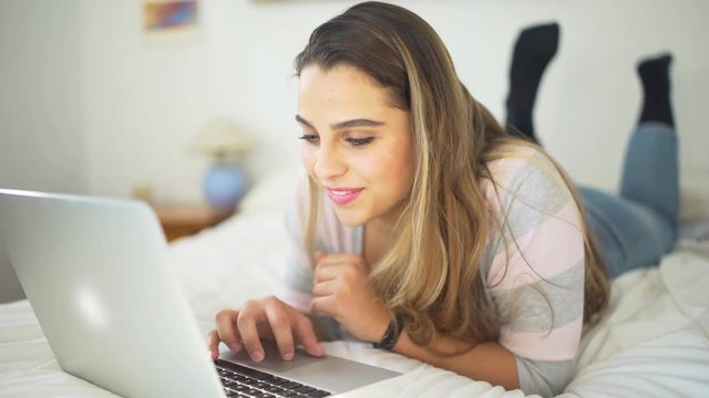 A beautiful woman studiying in the bedroom with laptop