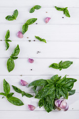 Fresh green basil leaves with garlic and pepper on white background. Flat lay.