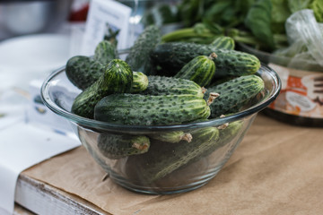 Harvest cucumbers in a basket on the wooden background.