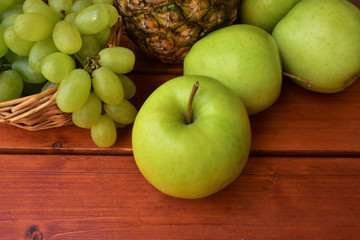 Green apples, grapes and pineapple on a table.