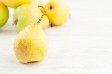 Heap of fresh ripe yellow whole pears and one pear separately on old rustic white wooden table