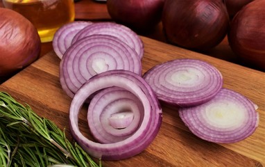 Red onion sliced in rings on a cutting board.
