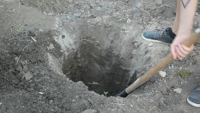 The man digging a hole with a shovel in the ground. Close up shot.