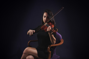 Woman playing violin on black background