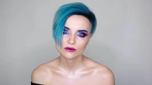 Close up of an attractive girl  with full make-up on and blue hair. Posing for camera. Beauty blog, social media trend.
