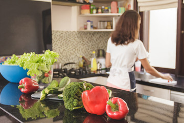 vegetables for ingredients on the table at kitchen with housewife at the background