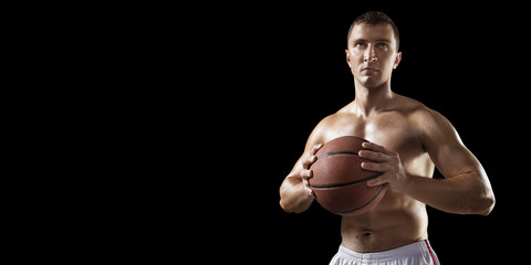 Fototapeta na wymiar Basketball player hold a basketball ball. Isolated basketball player on a black background. Basketball player with a naked torso and pumped muscles.