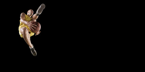 Basketball player makes slam dunk. Isolated basketball player on a black background. Player wears unbranded clothes. © Alex