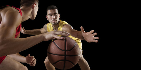 Two basketball players fight for the basketball ball. Isolated basketball players on a black...