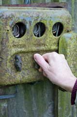 The hand of an elderly woman switches electricity on an old rusty retro rural switchboard.