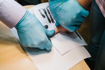The investigator takes fingerprints from the suspect in the crime. Investigation is a crime. Crime.