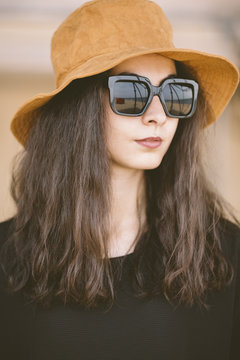 closeup of portrait of real young woman with hat and sunglasses