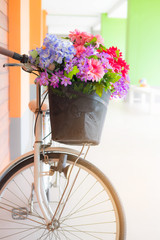 Fototapeta na wymiar Beautiful fake flowers in basket of old white bicycle with warm light