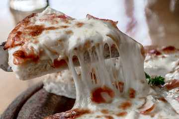 Close up Italian pizza about cheese it stick. Selective focus.Slice of hot pizza large cheese lunch...