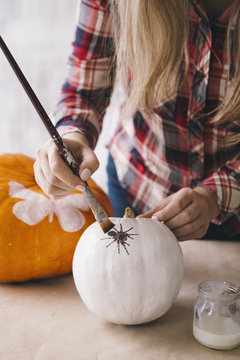 Woman painting white pumpkin with brush