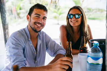 Young happy couple enjoying some drinks in a beach bar