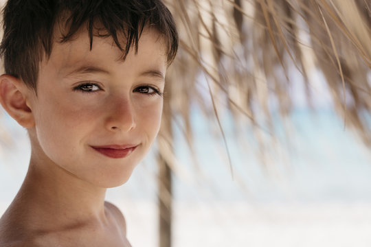 Headshot of a smiling boy looking at camera in a tropical Summer environment