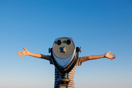 Child holds his arms out while looking through a viewfinder