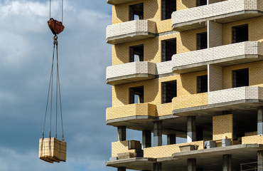 crane delivers construction materials to the construction of a house