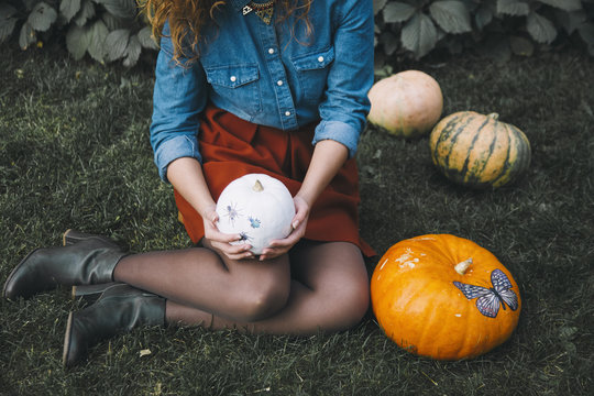 Woman holding white pumpkin sitting on grass