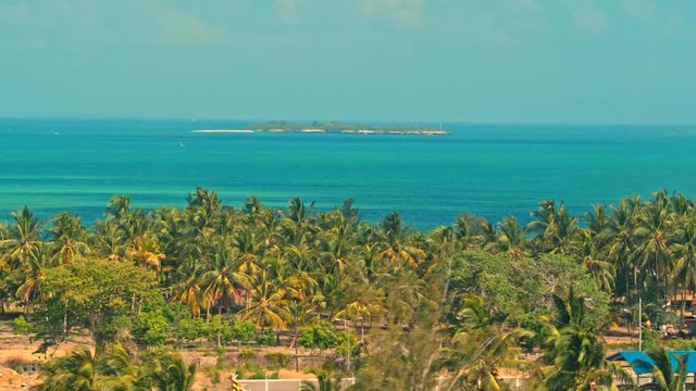 Cinematic aerial of resort coast of Indian Ocean beach near city of Dar es Salaam in Tanzania, Africa on a hot summer day with lush, green vegetation, palm trees, beaches with peaceful blue waves