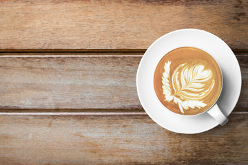 Cup of hot latte coffee us on top of wood table. Top view with copy space, flat lay.