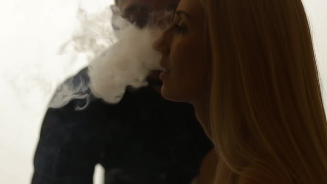 Man gives smoke kiss to woman. Vape culture