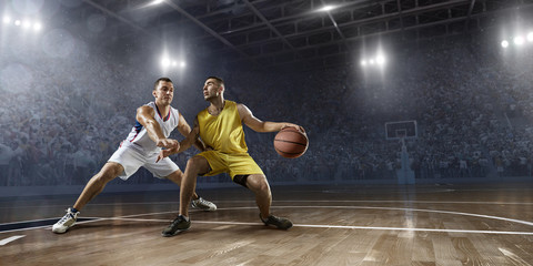 Fototapeta na wymiar Two basketball players fight for the basketball ball on big professional arena. Player wears unbranded clothes.