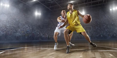  Two basketball players fight for the basketball ball on big professional arena. Player wears unbranded clothes. © Alex