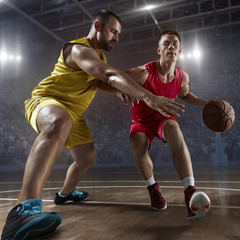 Fototapeta premium Two basketball players fight for the basketball ball on big professional arena. Player wears unbranded clothes.