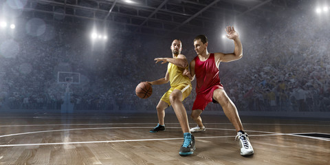 Plakat Two basketball players fight for the basketball ball on big professional arena. Player wears unbranded clothes.