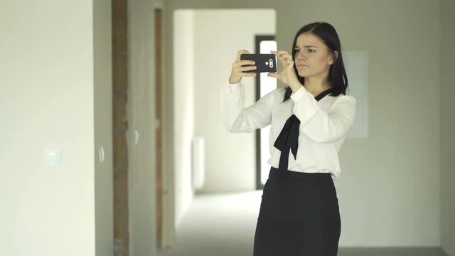 Female real estate agent talking photos with cellphone of new home 
