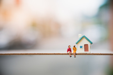 Miniature people, couple woman sitting in front of house