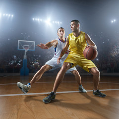 Two basketball players fight for the basketball ball on big professional arena. Player wears unbranded clothes. © Alex