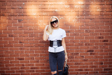 Fototapeta na wymiar Beautiful blonde caucasian woman standing in front of brick wall