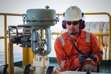 Operator or worker recording operation data of oil and gas process at production plant, Offshore oil and gas industry in the sea or gulf, Operator monitor production process and routine daily record.