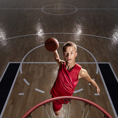 Basketball player makes slam dunk on big professional arena. Player flies through the air with the...