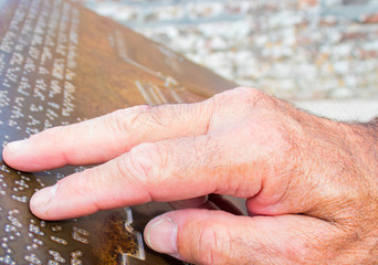 The hand touches the metal plate written in the Braille letters. This helps the blind to recognize and communicate through the text.