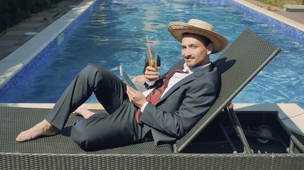 Young woman drinks cocktail from businessman hand laying near swimming pool - Powered by Adobe