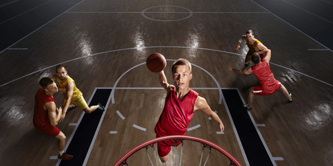 Basketball player makes slam dunk on big professional arena. Player flies through the air with the...