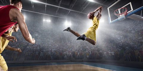 Basketball player makes slam dunk on big professional arena. Player flies through the air with the...