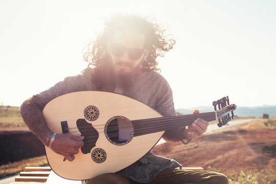 Portrait of Bearded Young Hippie Wearing Sunglasses and Playing Oud (Mandolin)