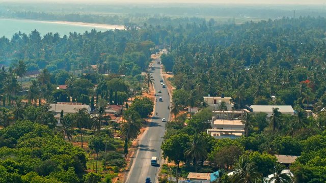 Cinematic aerial of busy traffic on streets of city of Dar es Salaam by Indian ocean in Tanzania, Africa. Cars, busses, motorcycles, pedestrians, lush, green vegetation, palm trees, hot summer day
