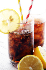 Softdrink with ice cubes, lemon and straw in glass
