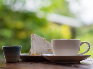 Coffee and cake on table with blurred green background
