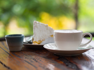 Coffee and cake on table with blurred green background